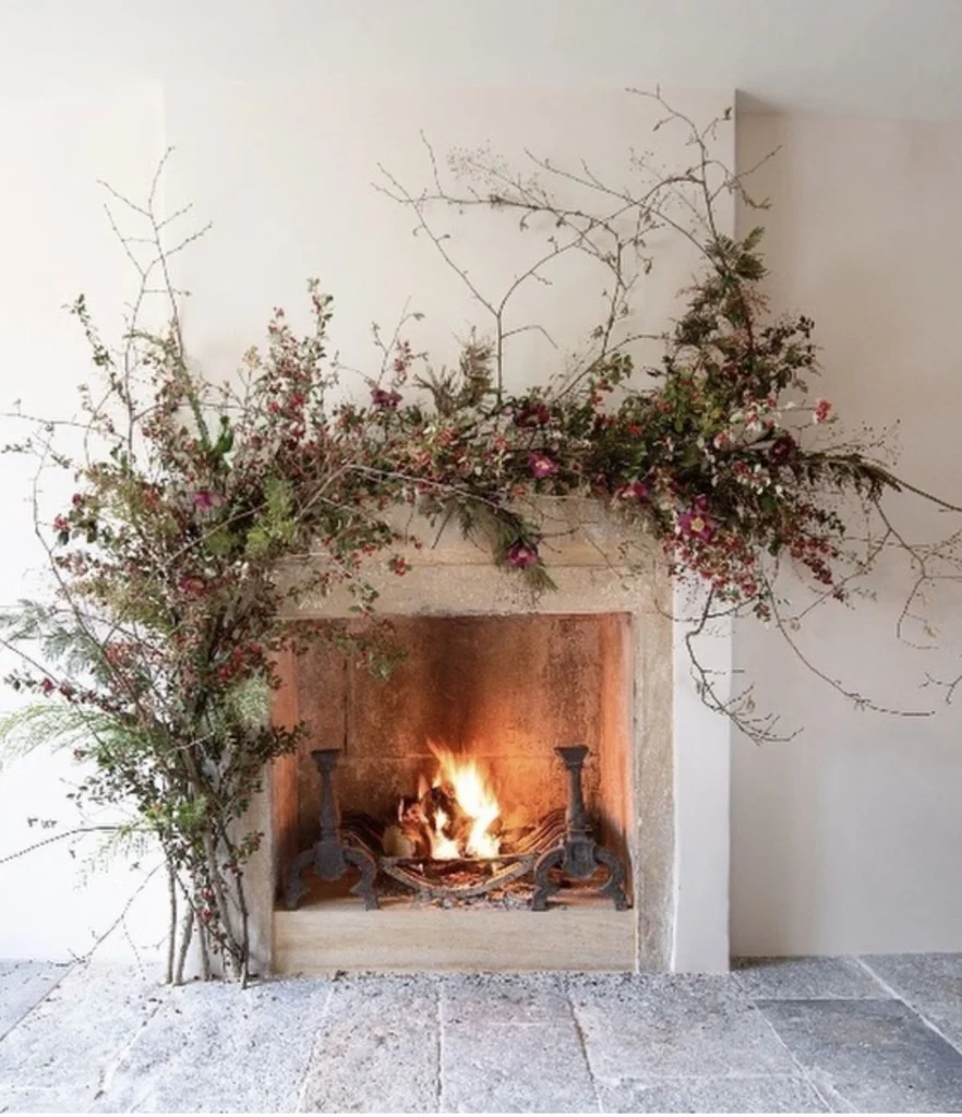 praznična okrasitev kamina z vejami in naravnimi materiali